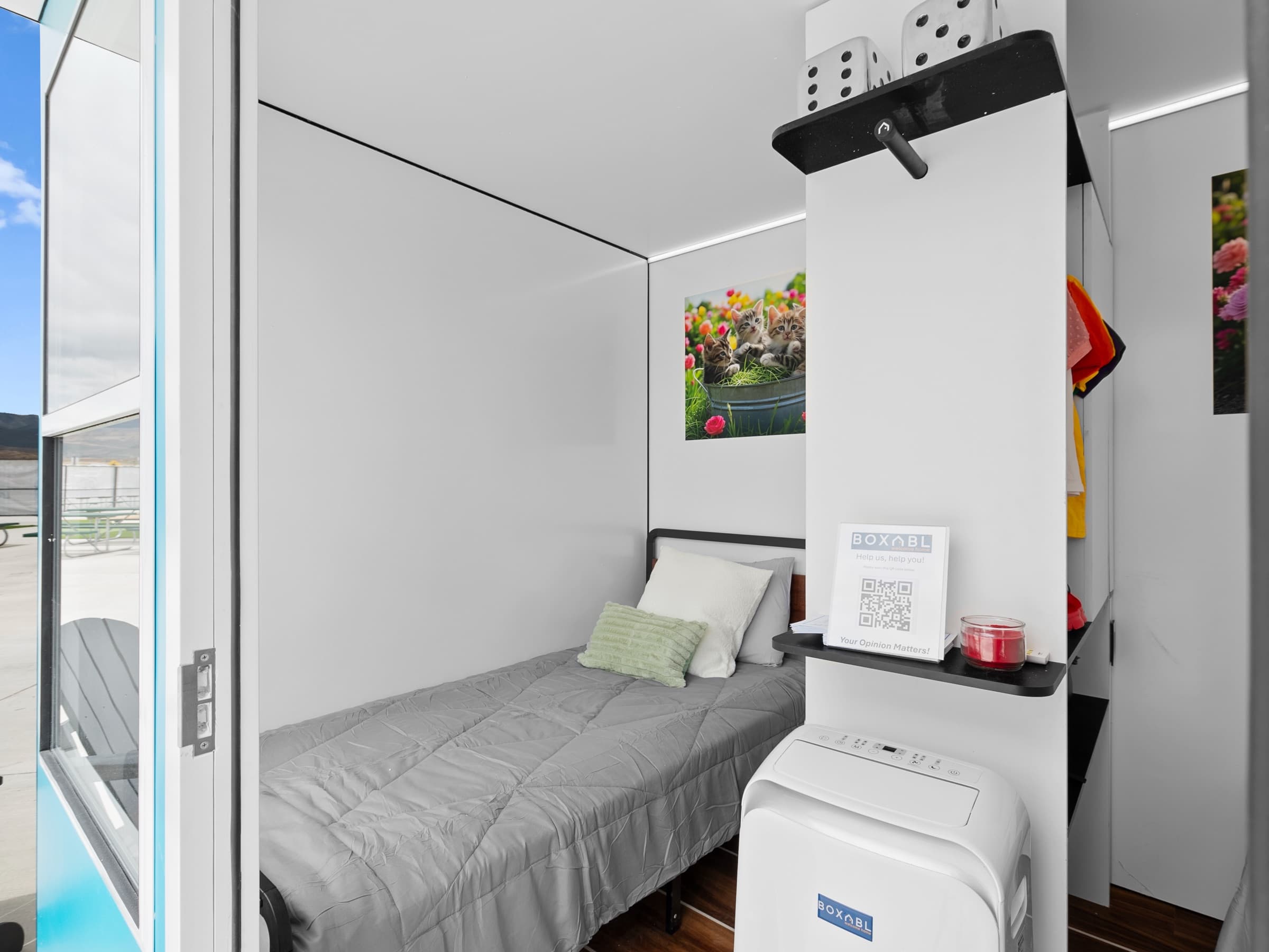 Interior of a Sanctuary unit with the door open to daylight, bed and hanging storage visible