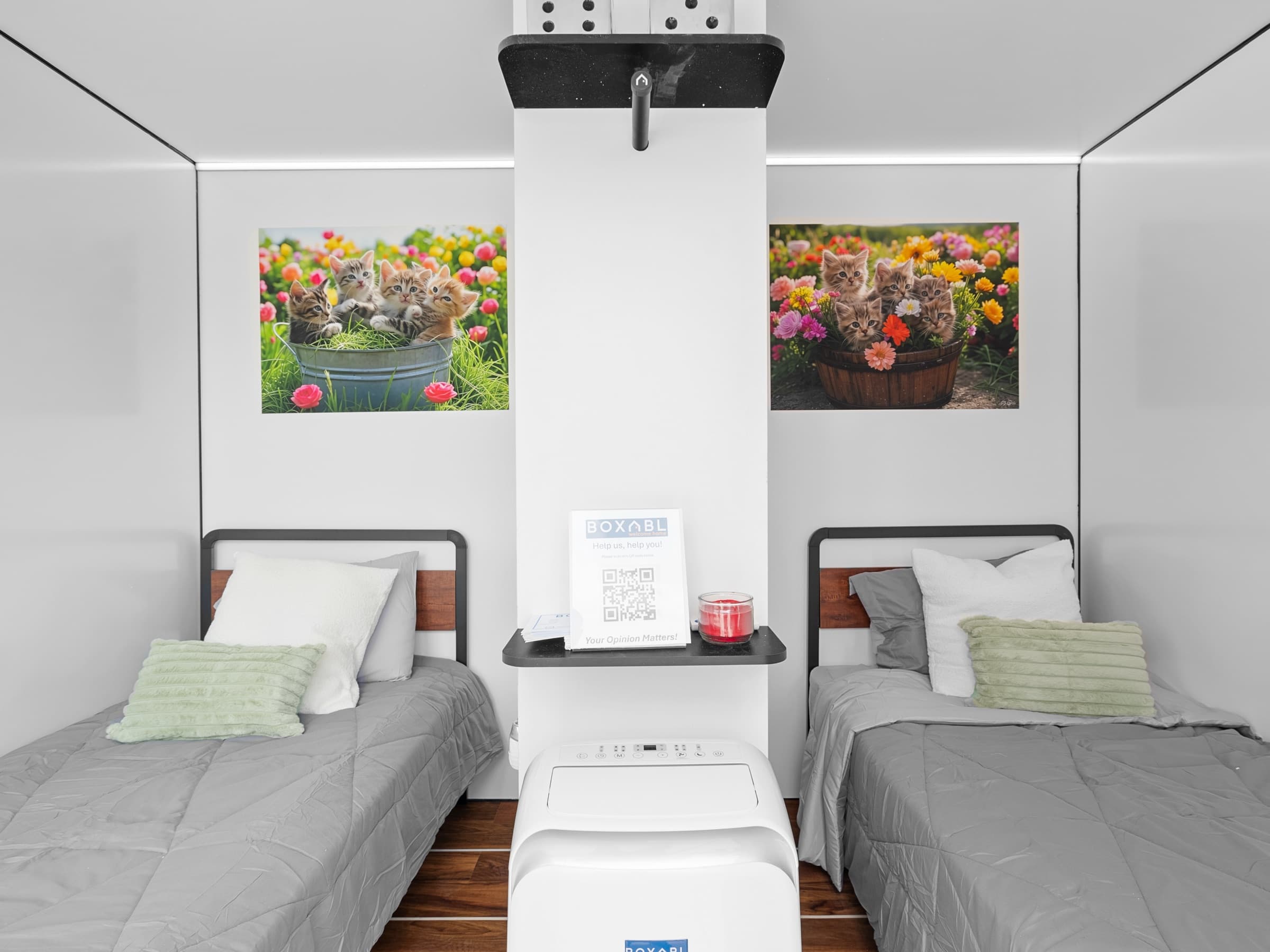Interior of a Sanctuary Sleep 2 unit with two twin beds, artwork, and a climate unit between them